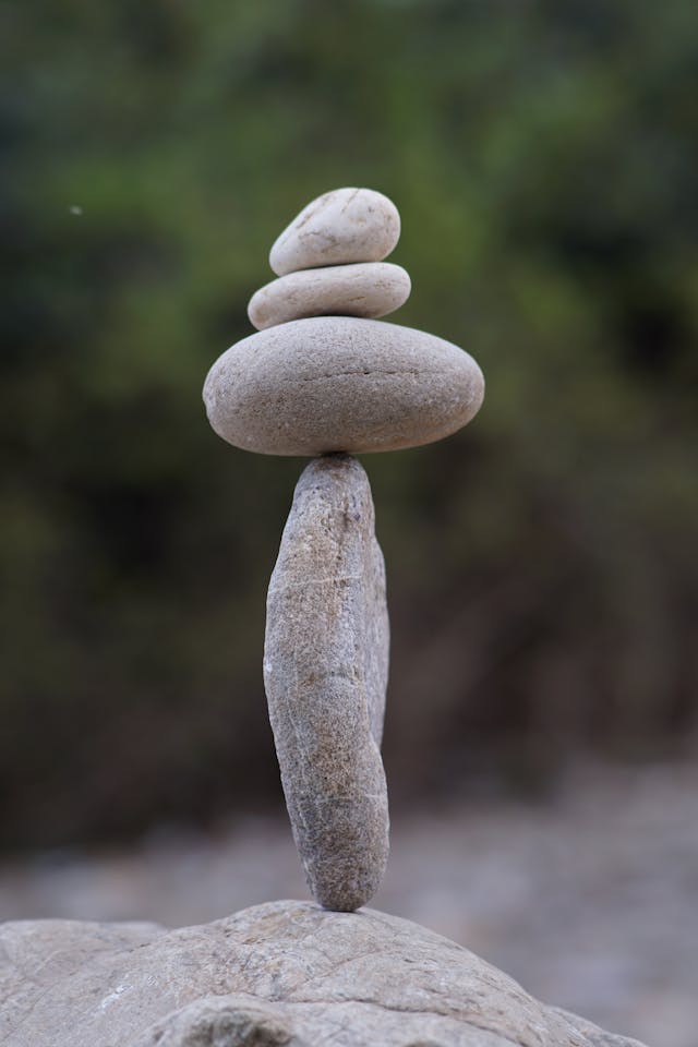 Four smooth rocks balanced perfectly on top of each other in a tall stack.