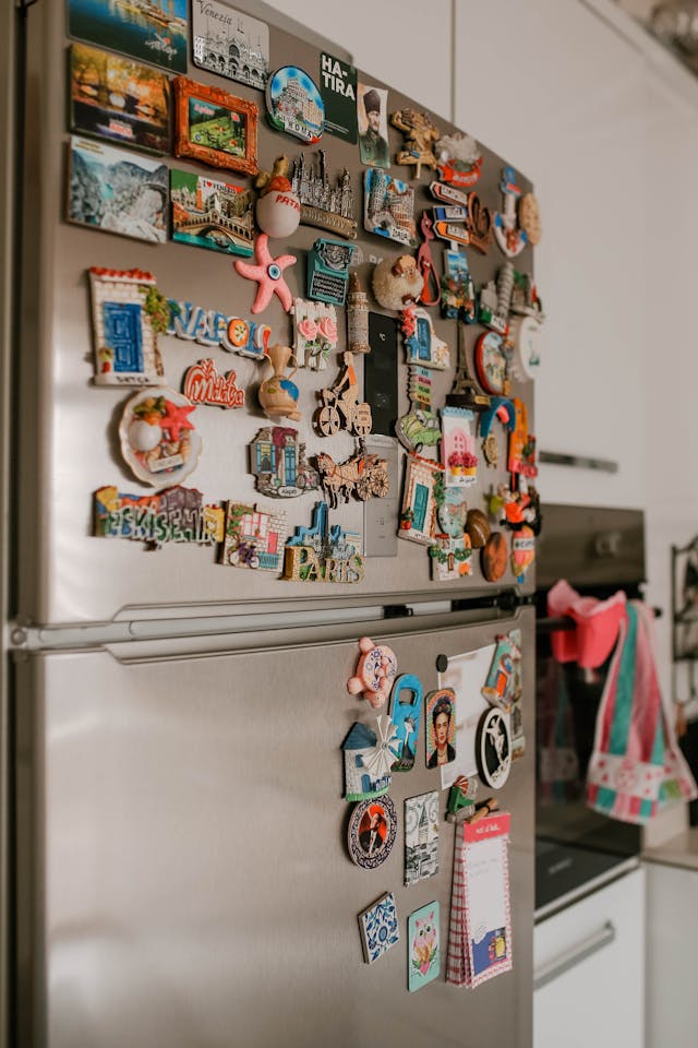 A refrigerator covered in many colorful souvenir magnets.