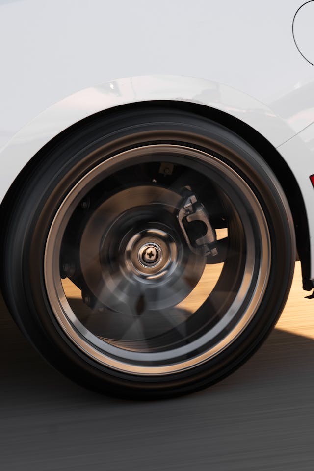 A close-up of a car wheel spinning quickly while driving down a road.