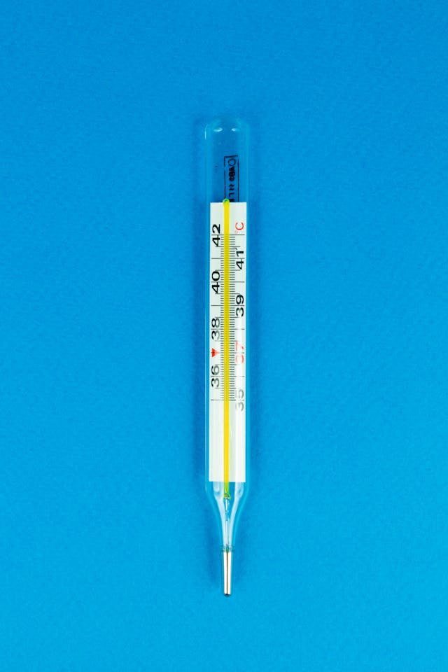 A glass thermometer showing a temperature reading against a bright blue background.